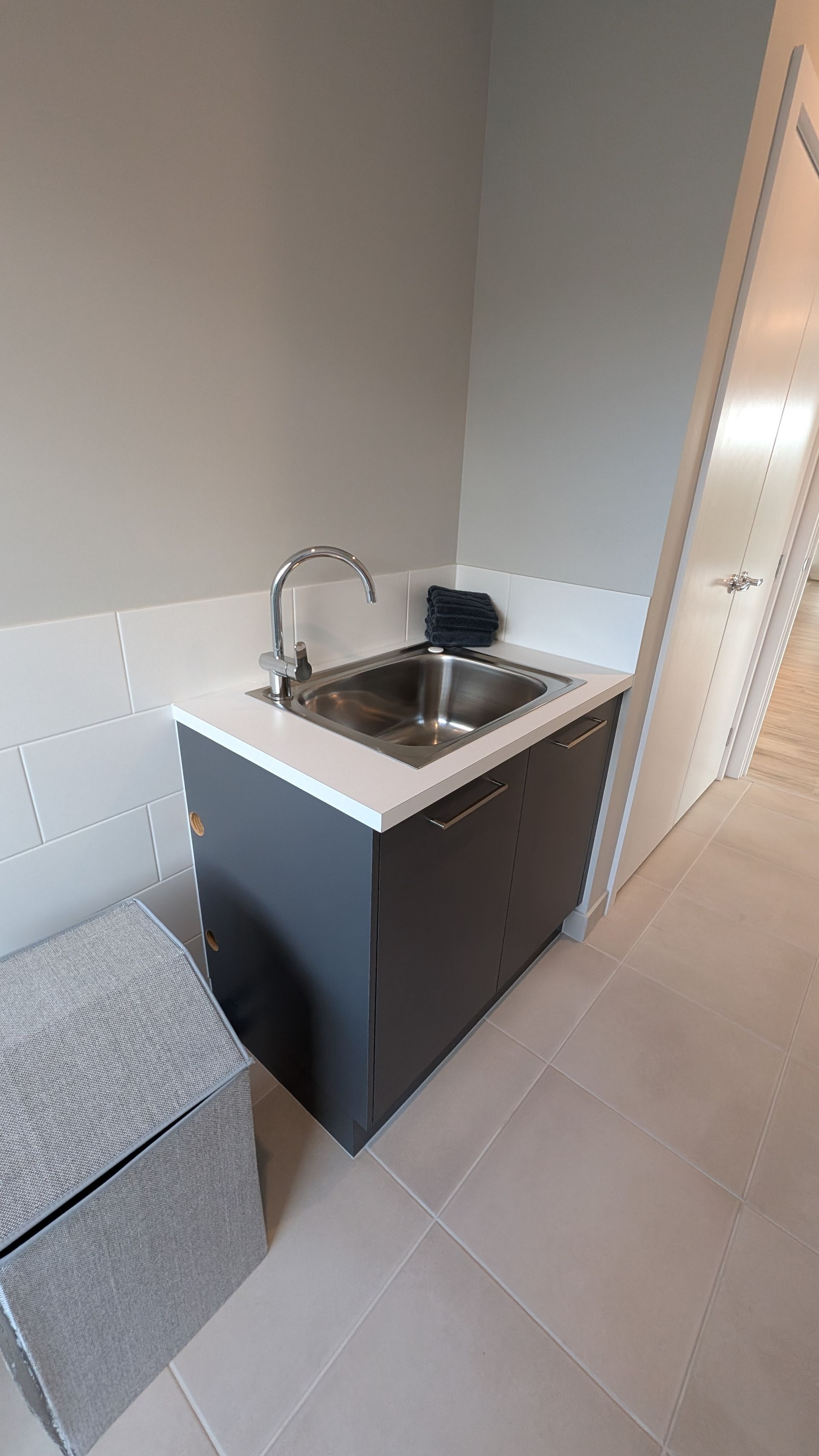 A laundry room with a sink and a stool.