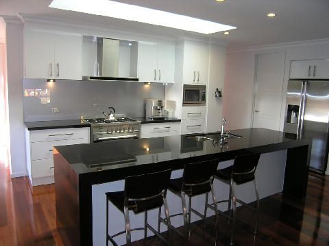 A kitchen with white cabinets and black counter tops