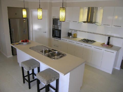 A kitchen with white cabinets and stools and a large island