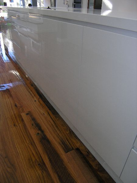 A kitchen with white cabinets and a wooden floor.