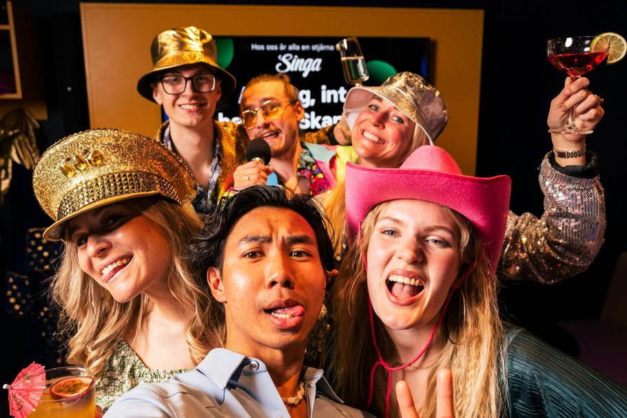 Smiling people in gold and pink party hats posing for a selfie at a celebration