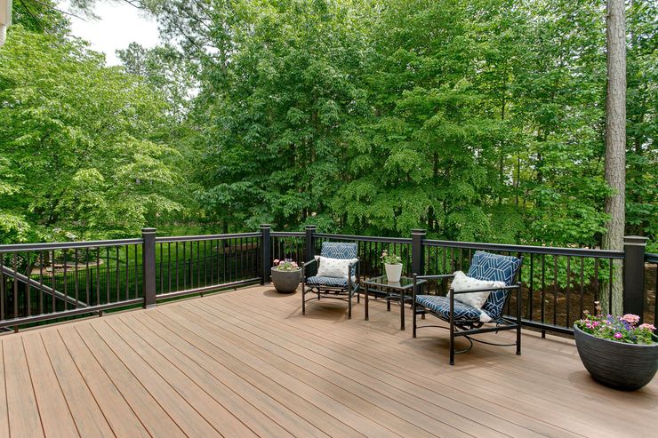 Terrasse en bois avec mobilier de jardin face à une forêt dense.