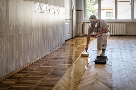 Un ouvrier lave un parquet brillant dans une pièce lumineuse