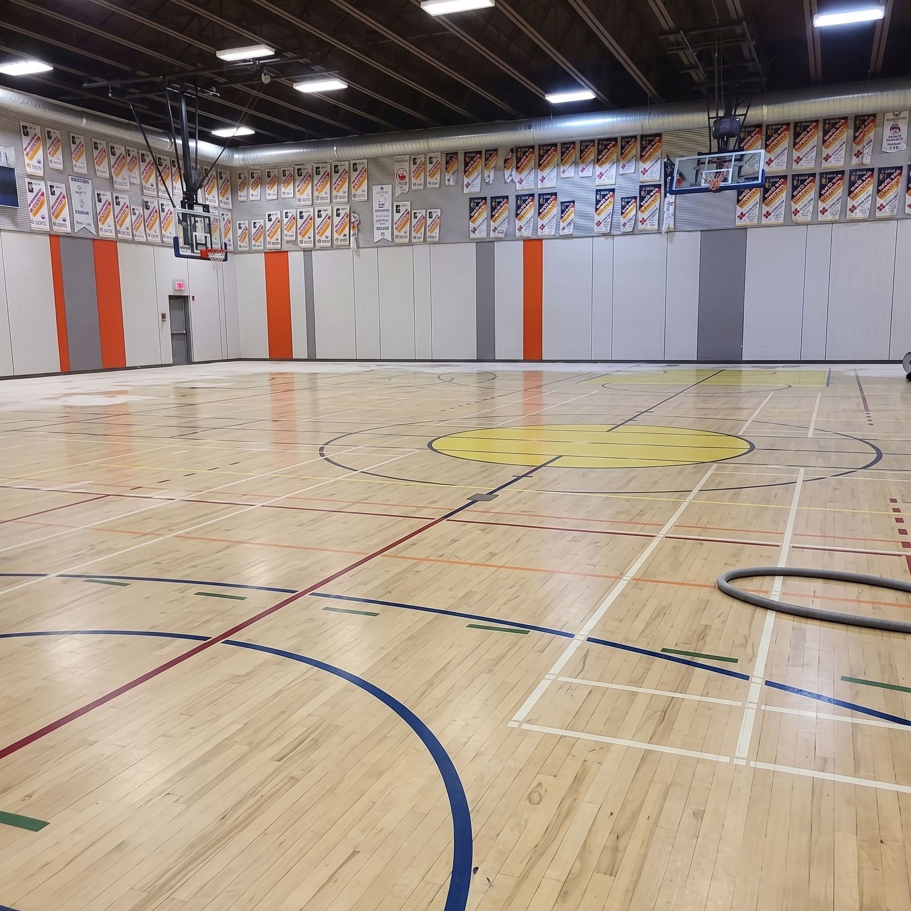 Gymnase intérieur vide avec un parquet ciré, des lignes de terrain peintes et un mur de bannières en arrière-plan