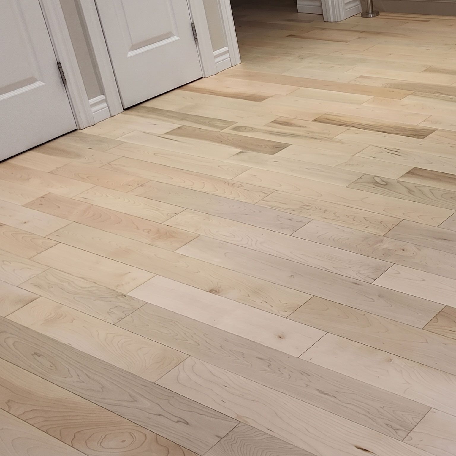 Parquet clair dans un couloir avec portes et plinthes blanches