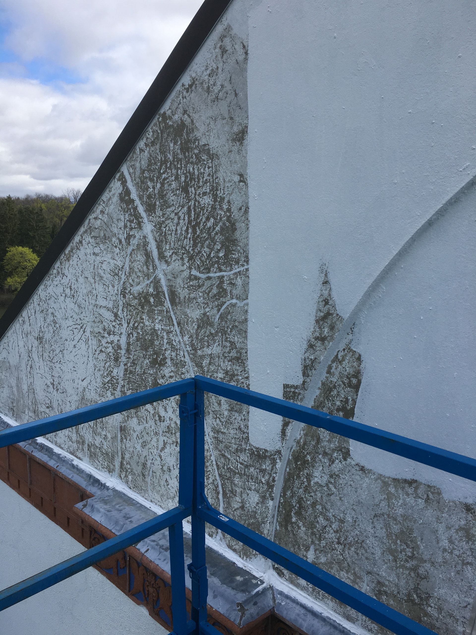 There is a blue railing on the side of a building.