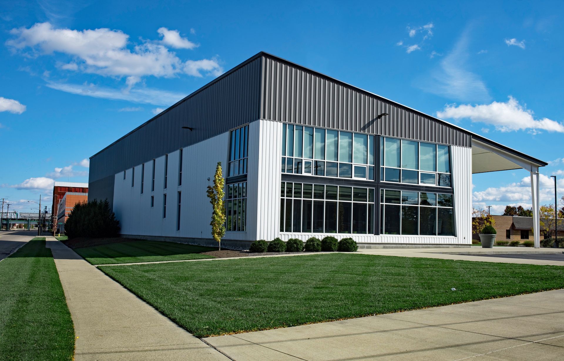 A large white building with a lot of windows is sitting on top of a lush green field.