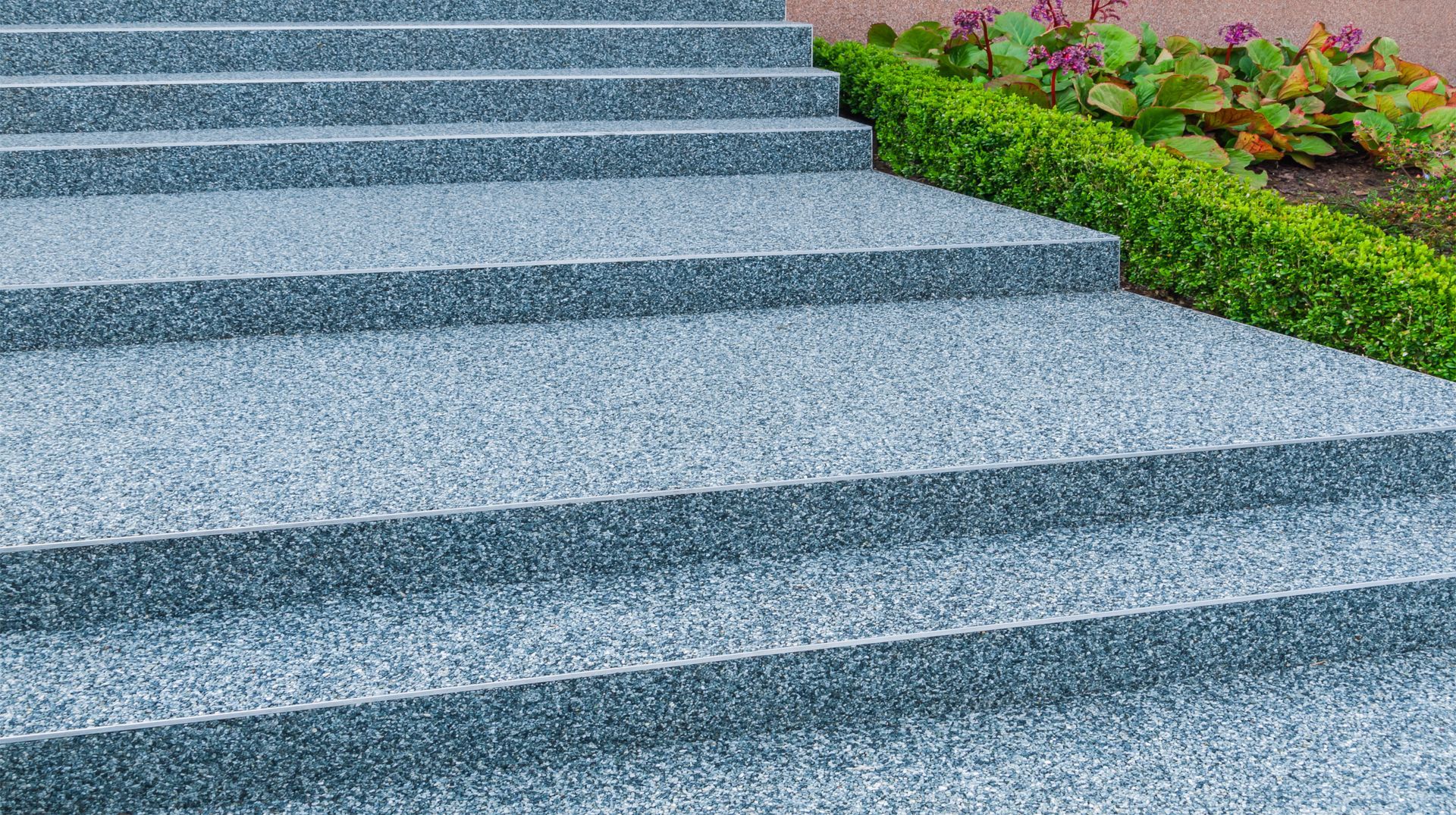 A close up of a set of stairs with a bush in the background.