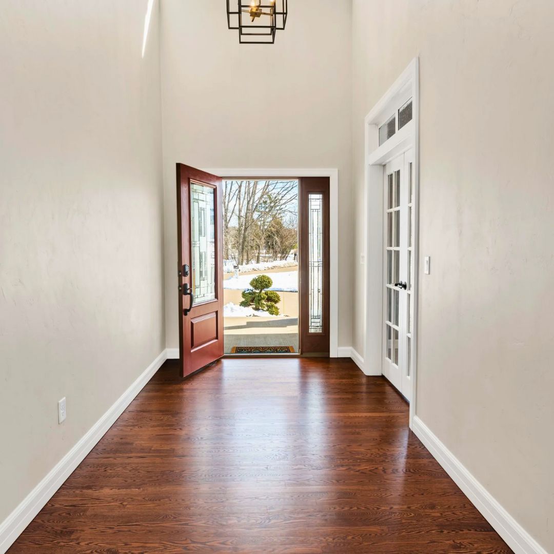 A hallway with hardwood floors and a door that is open
