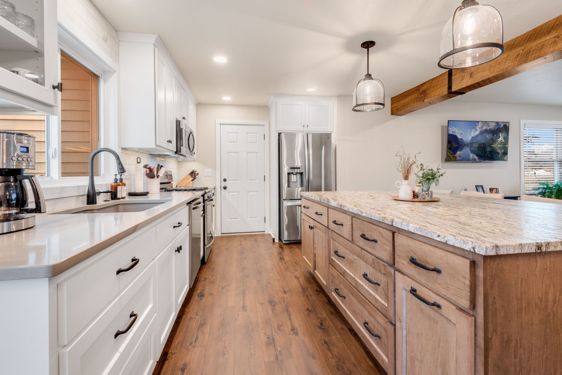 A kitchen with white cabinets , granite counter tops , stainless steel appliances and a large island.