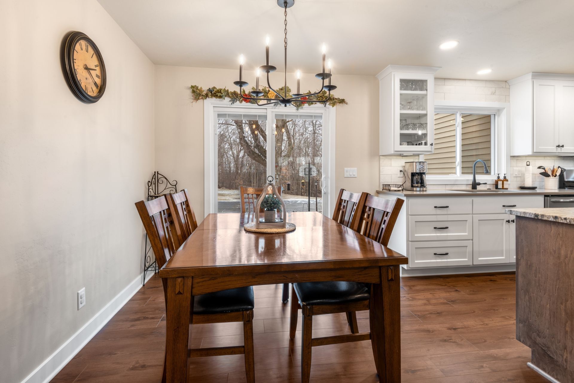 A dining room with a wooden table and chairs and a clock on the wall.