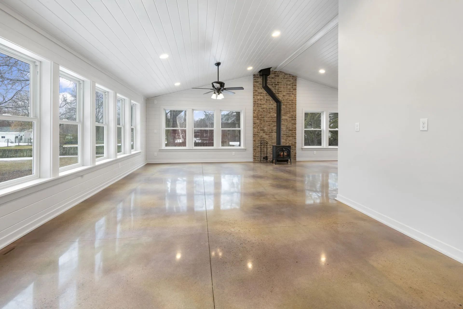 An empty living room with a ceiling fan and a fireplace.