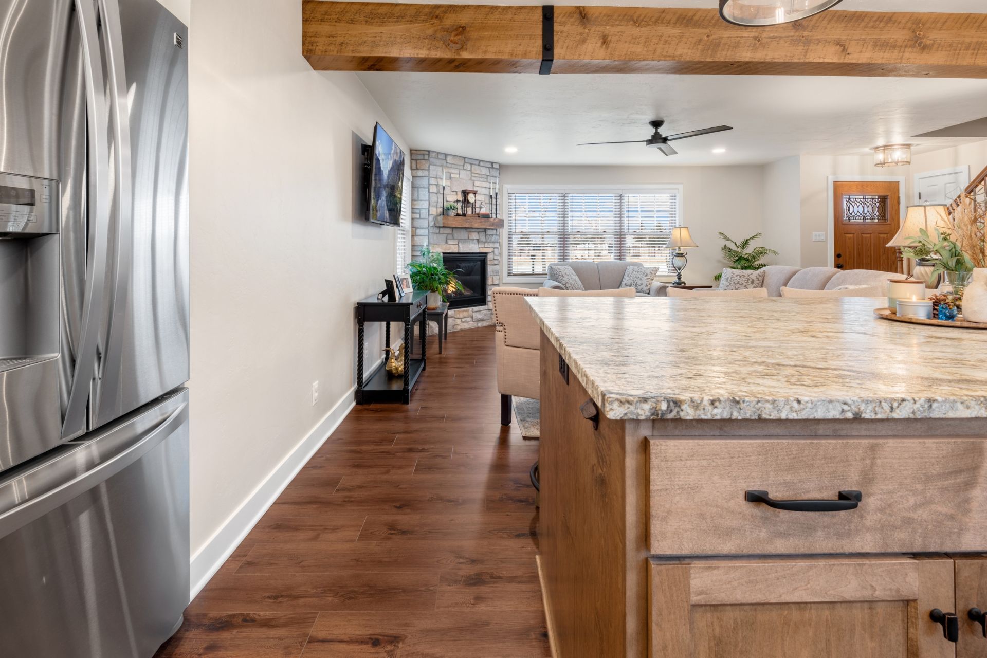A kitchen with a stainless steel refrigerator , granite counter tops , and wooden cabinets.