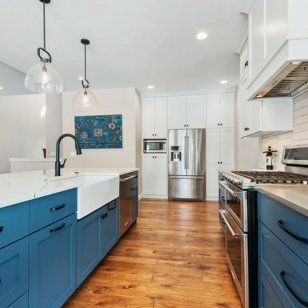 A kitchen with blue cabinets , stainless steel appliances , a sink , and a refrigerator.