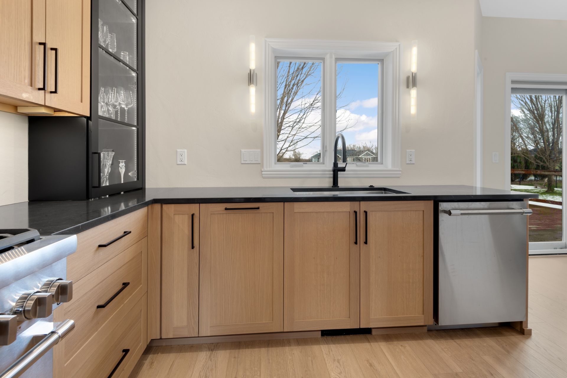 A kitchen with wooden cabinets , stainless steel appliances , a sink , and a window.