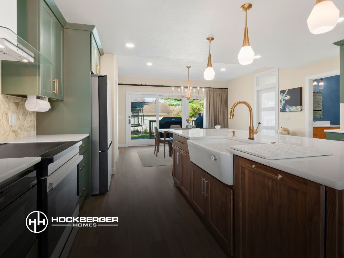 A kitchen with green cabinets , white counter tops , a sink and a refrigerator.