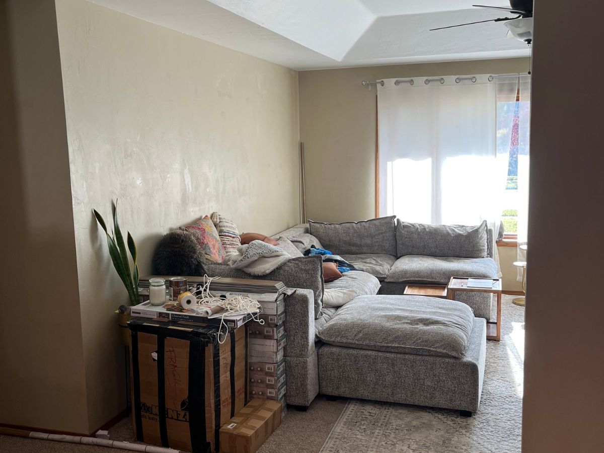 A living room with a sectional couch and a ceiling fan.