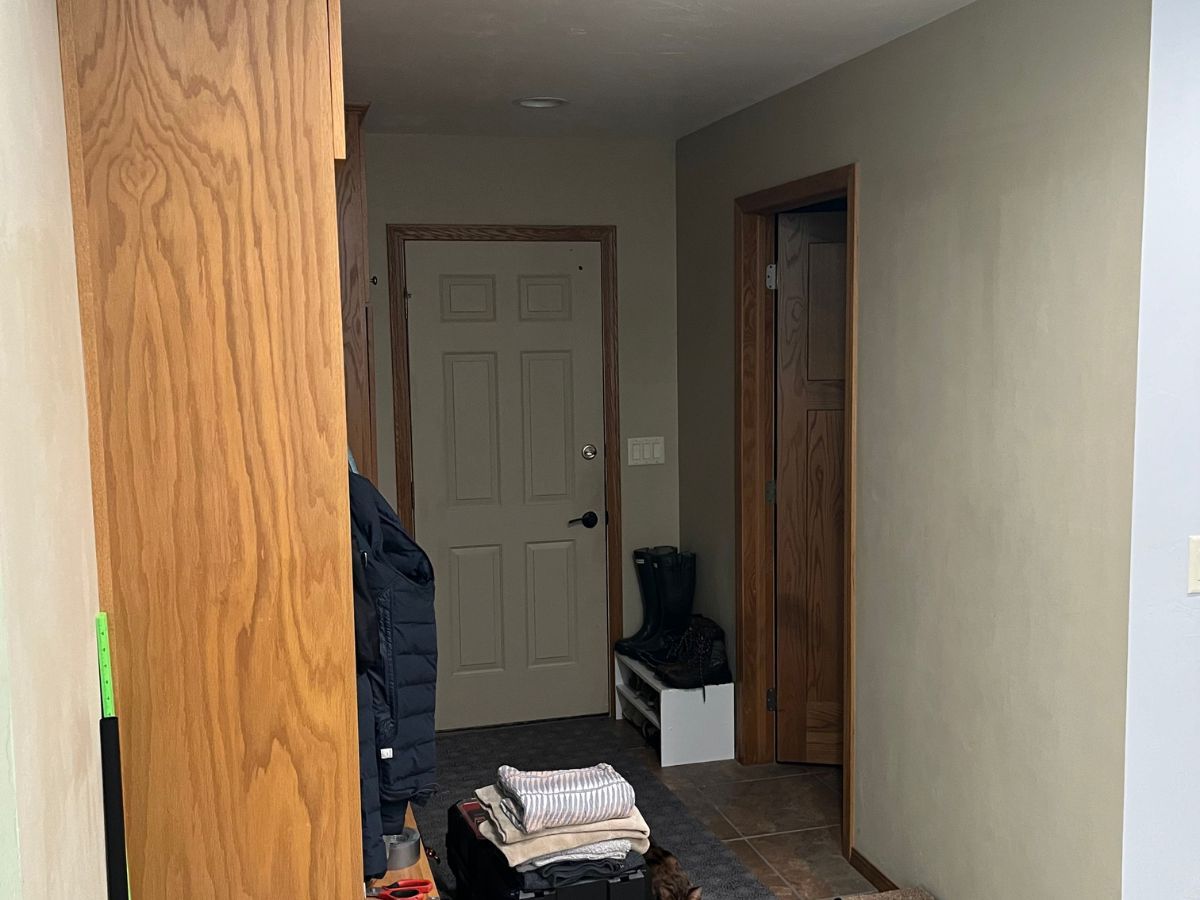 A hallway with a wooden cabinet and a door.