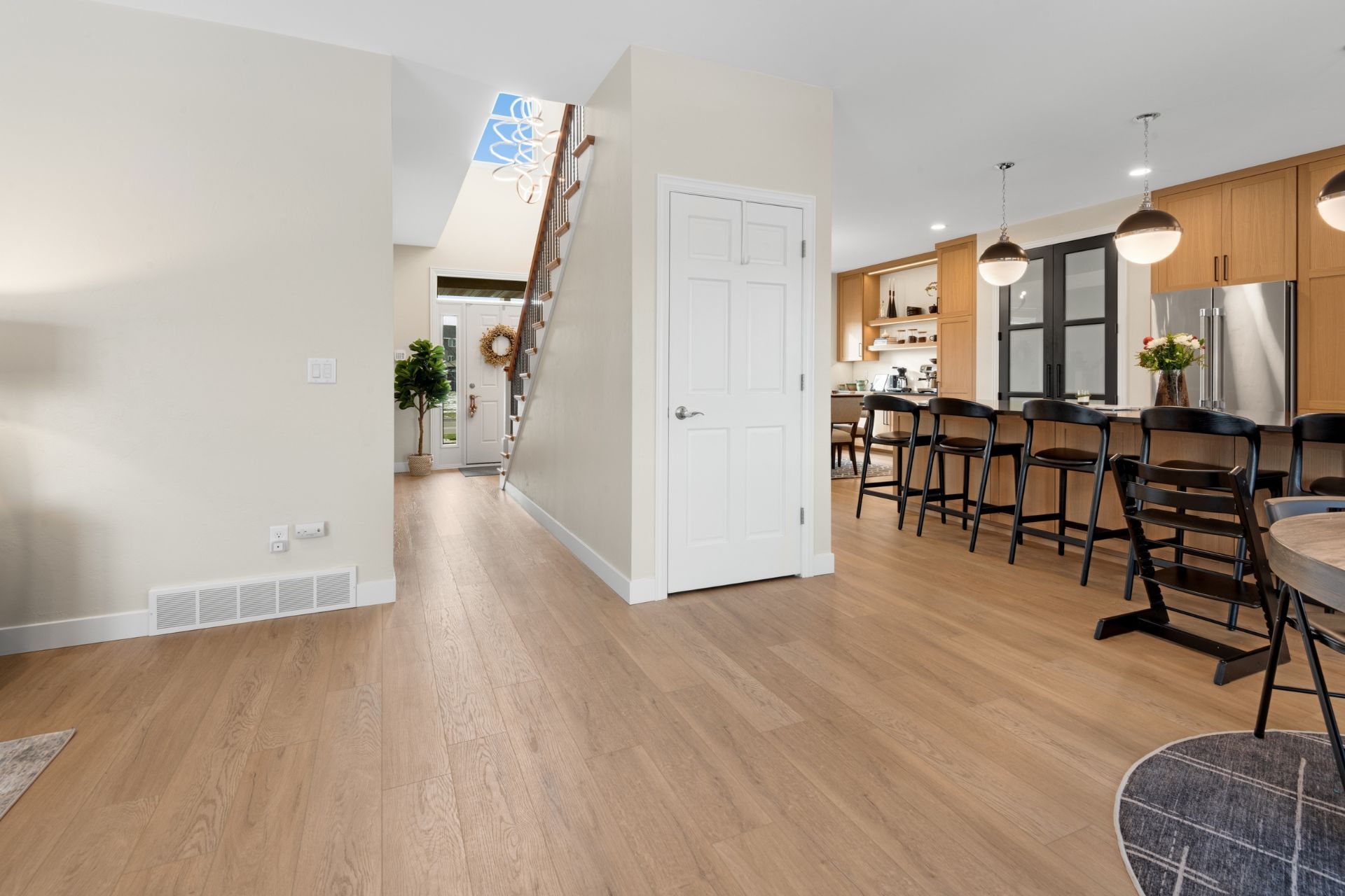 A living room with hardwood floors and a kitchen with stainless steel appliances.