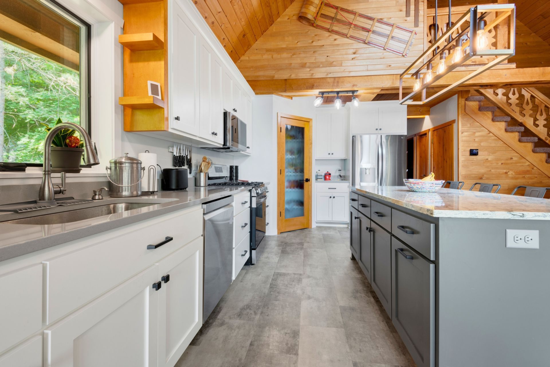 A kitchen with white cabinets , stainless steel appliances , and a large island.