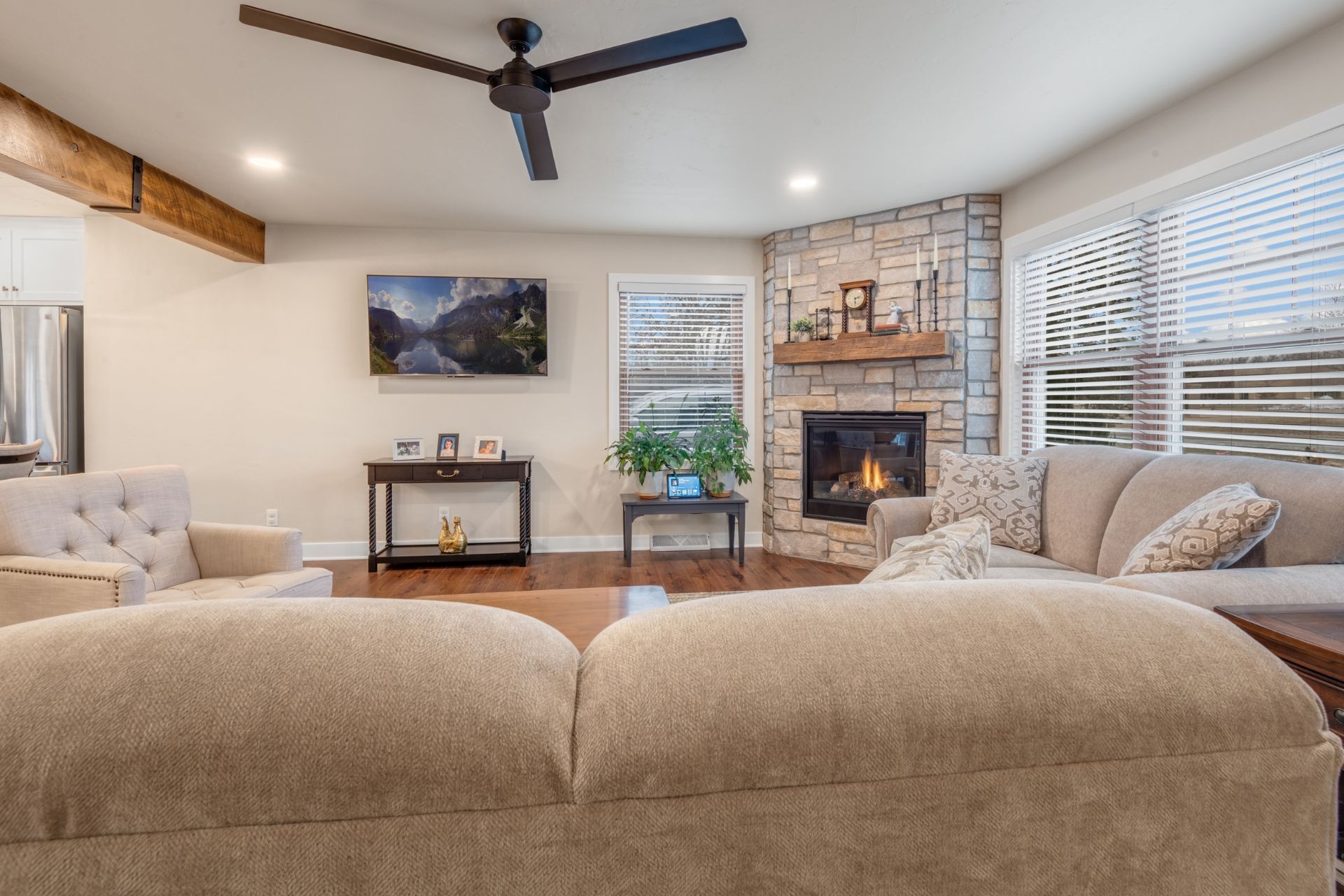A living room with a couch , chairs , a fireplace and a ceiling fan.