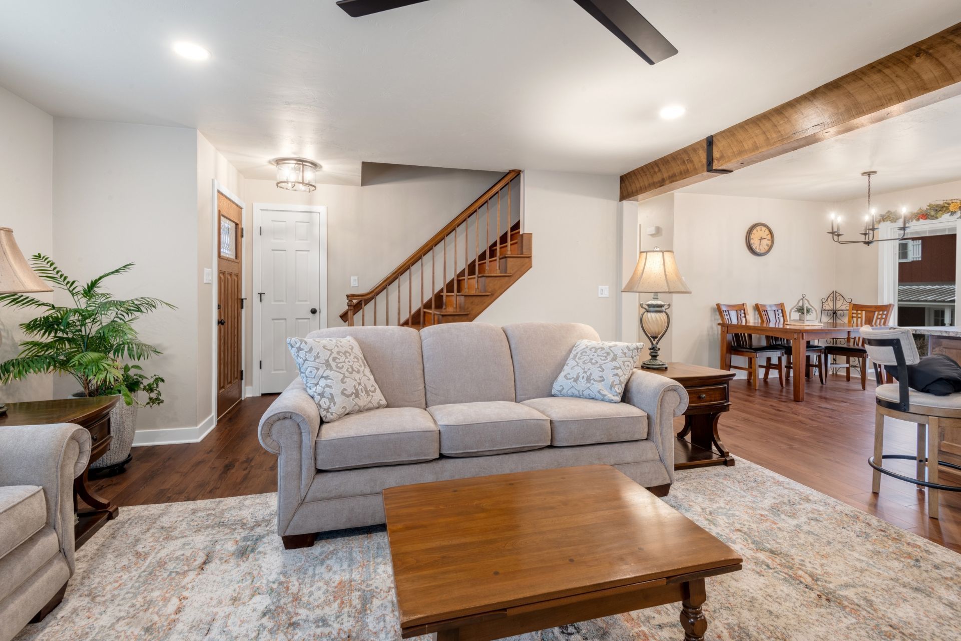 A living room with a couch , coffee table , chairs and stairs.