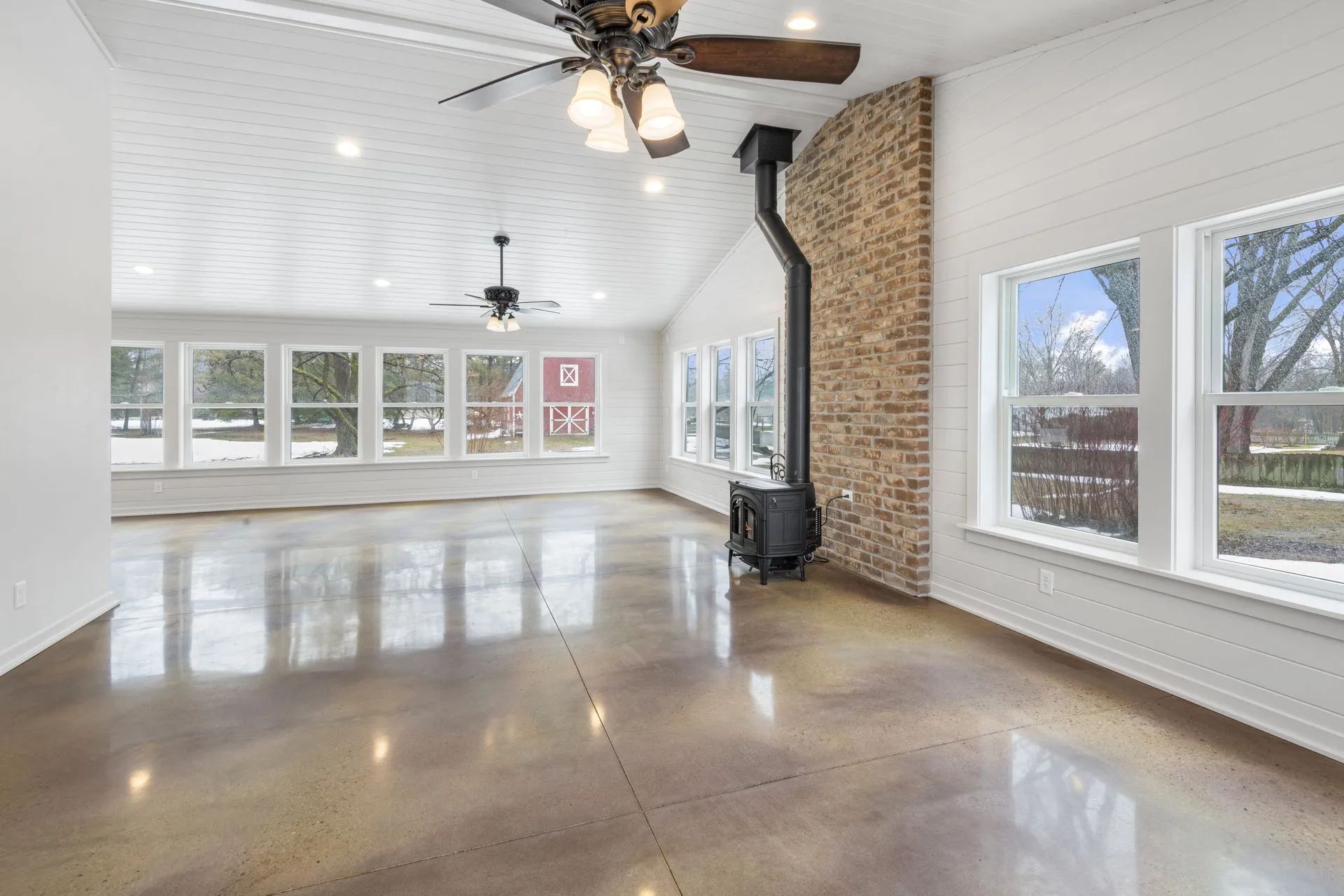 An empty living room with a ceiling fan and a wood stove.