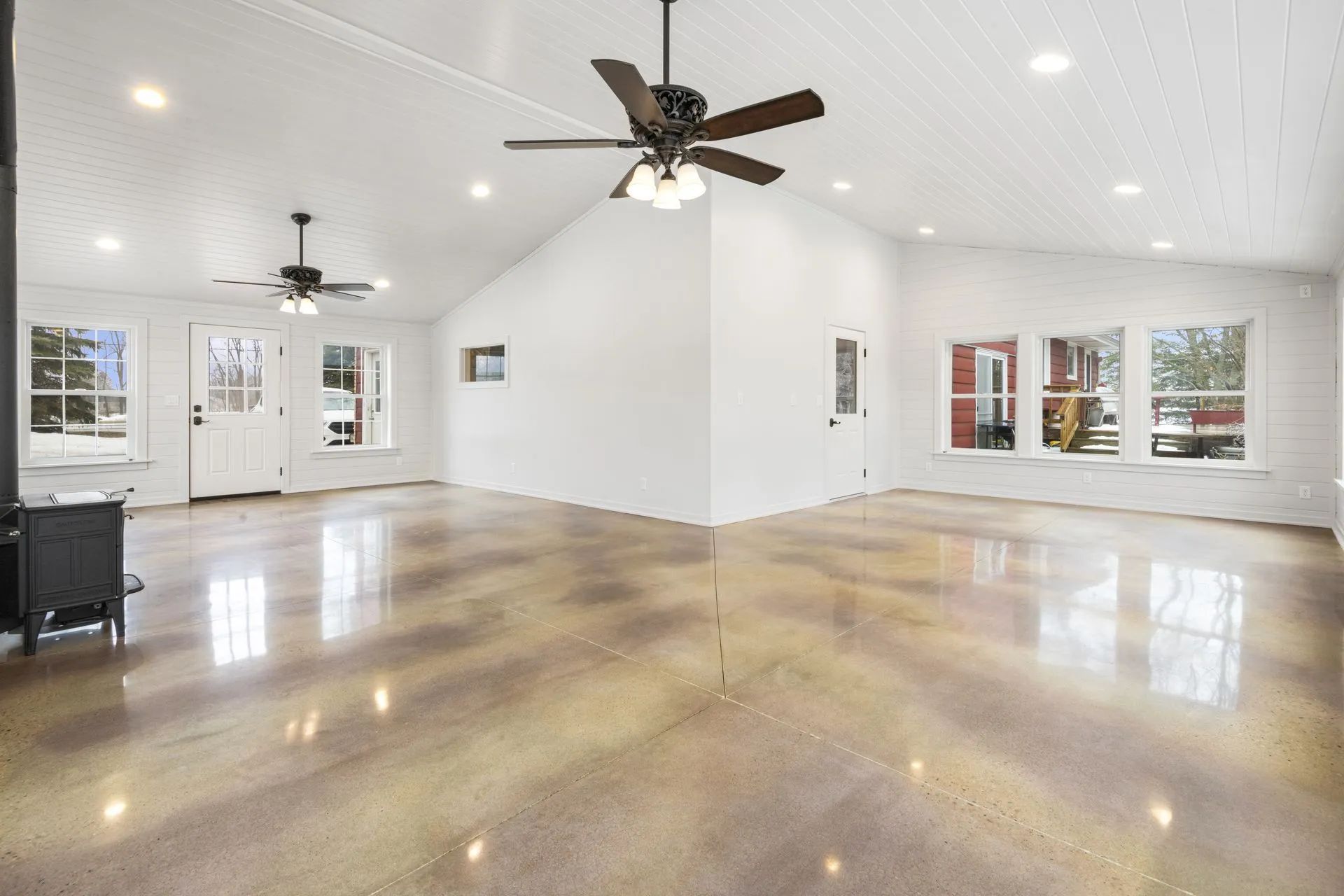 A large empty room with a ceiling fan and a concrete floor.