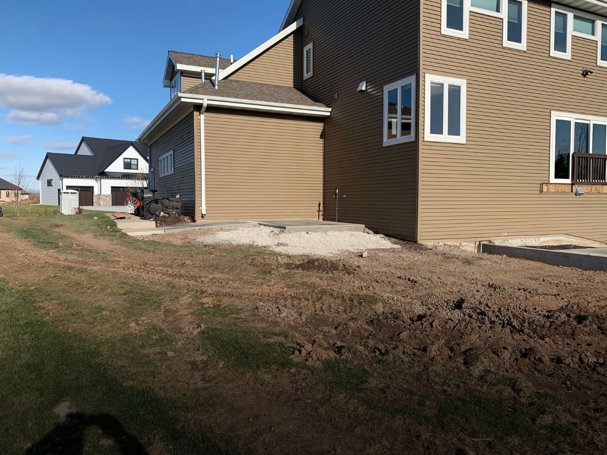A large house with a lot of windows is sitting on top of a dirt field.