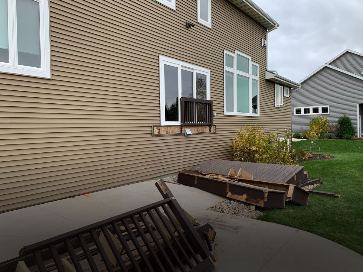 A house with a broken deck in front of it.