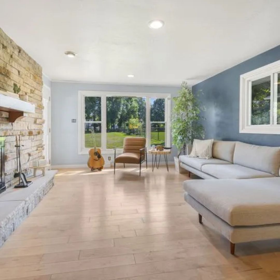 A living room with a couch , chair , fireplace and guitar.