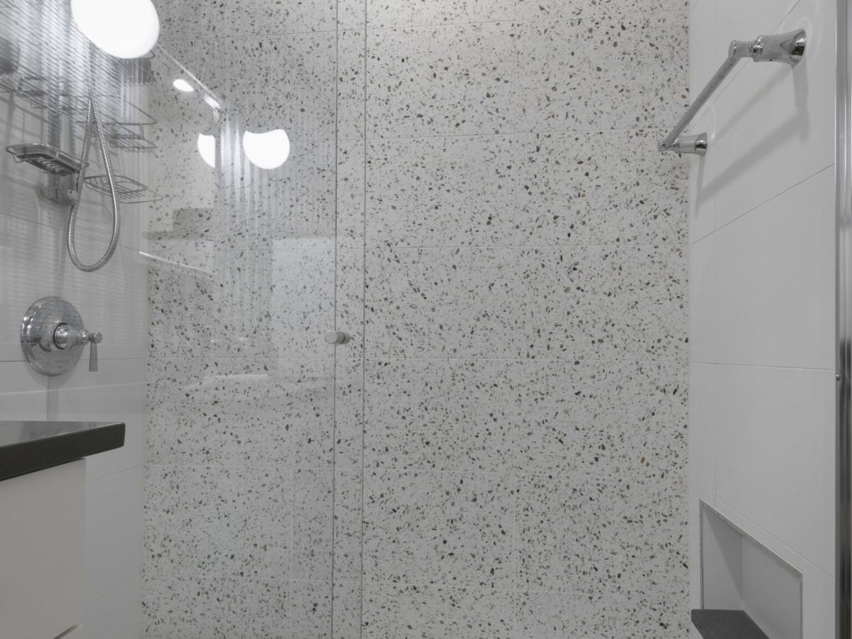 A bathroom with a walk in shower with a glass door.