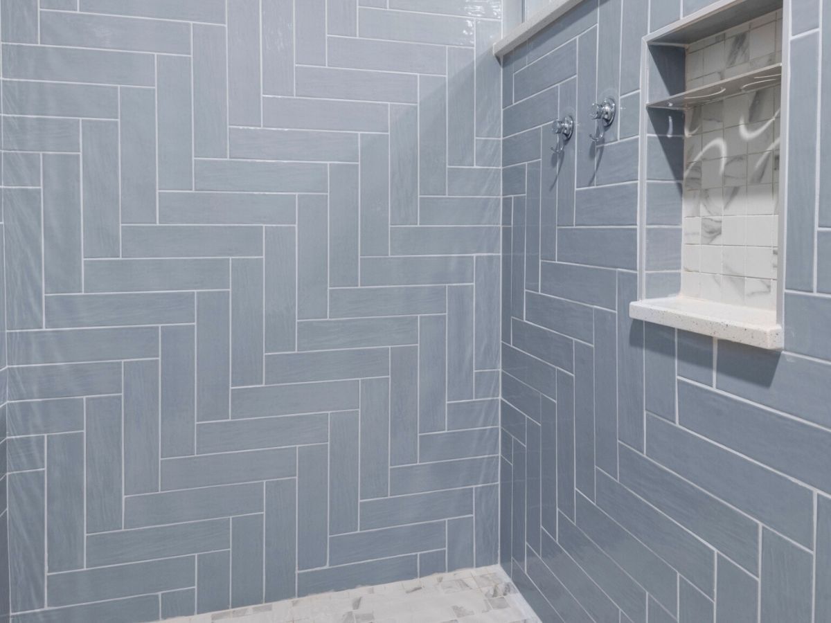 A bathroom with blue tiles and a walk in shower.