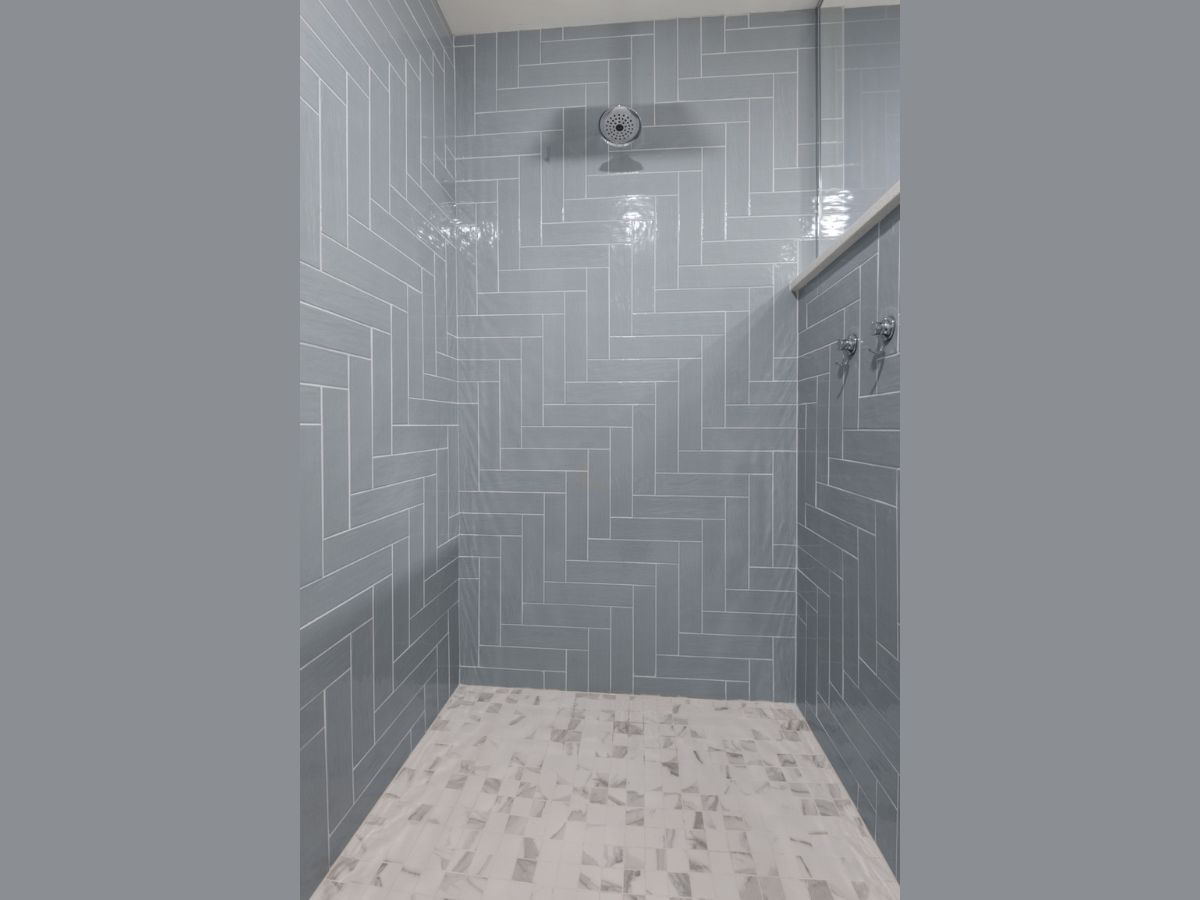 A shower with blue tiles and a white floor.