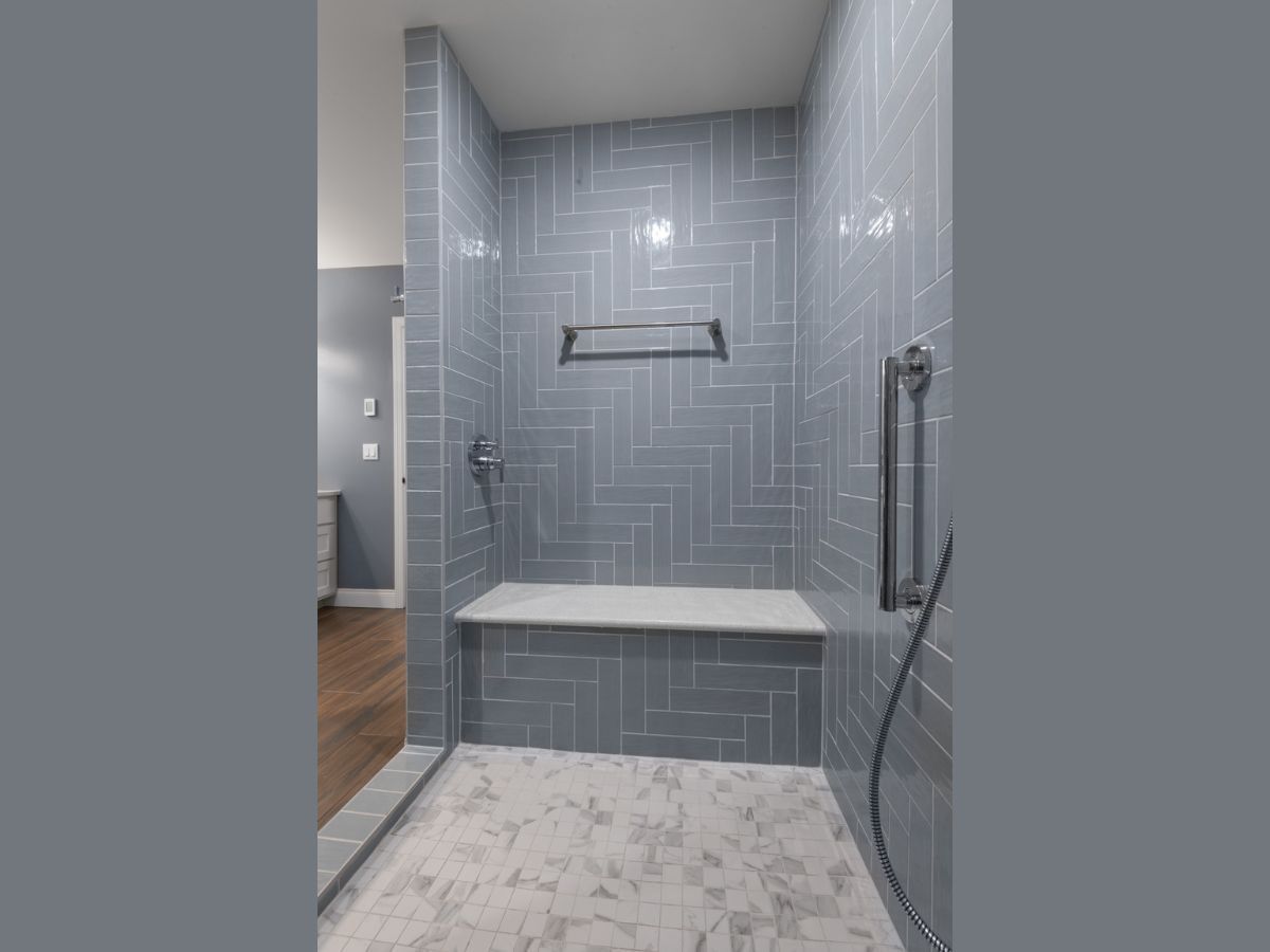 A bathroom with a walk in shower and a bench.