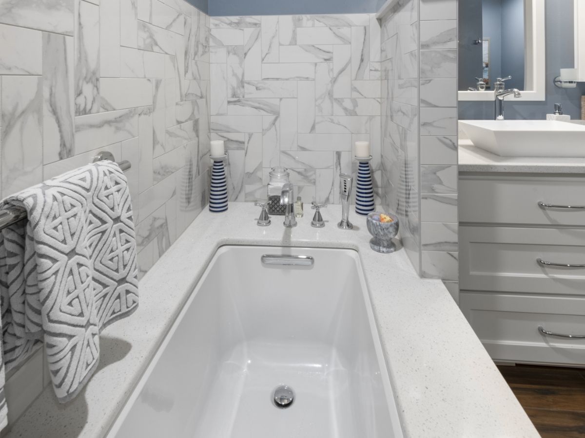 A bathroom with a bathtub , sink and mirror.