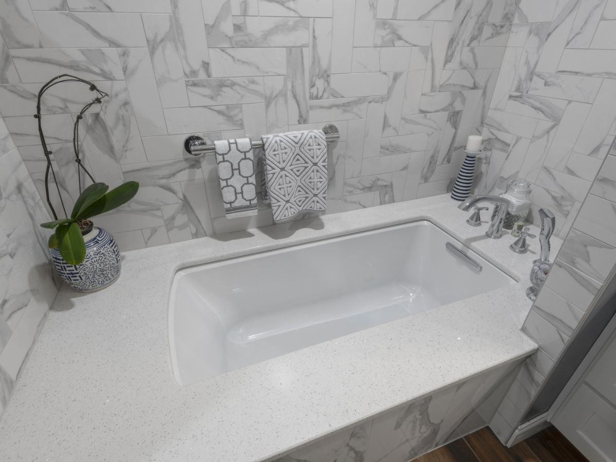 A bathroom with a bathtub , sink , and mirror.