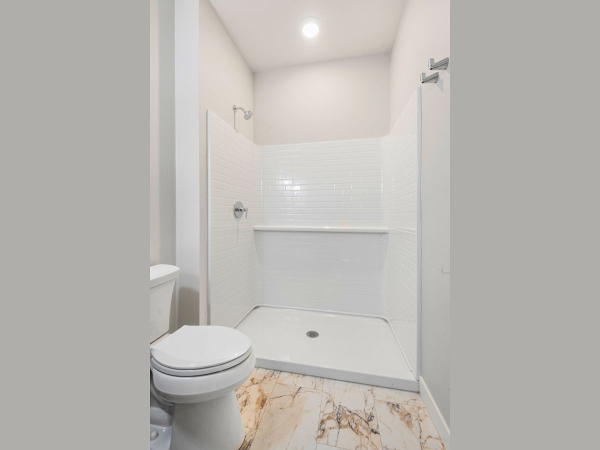 A bathroom with a toilet and a walk in shower.