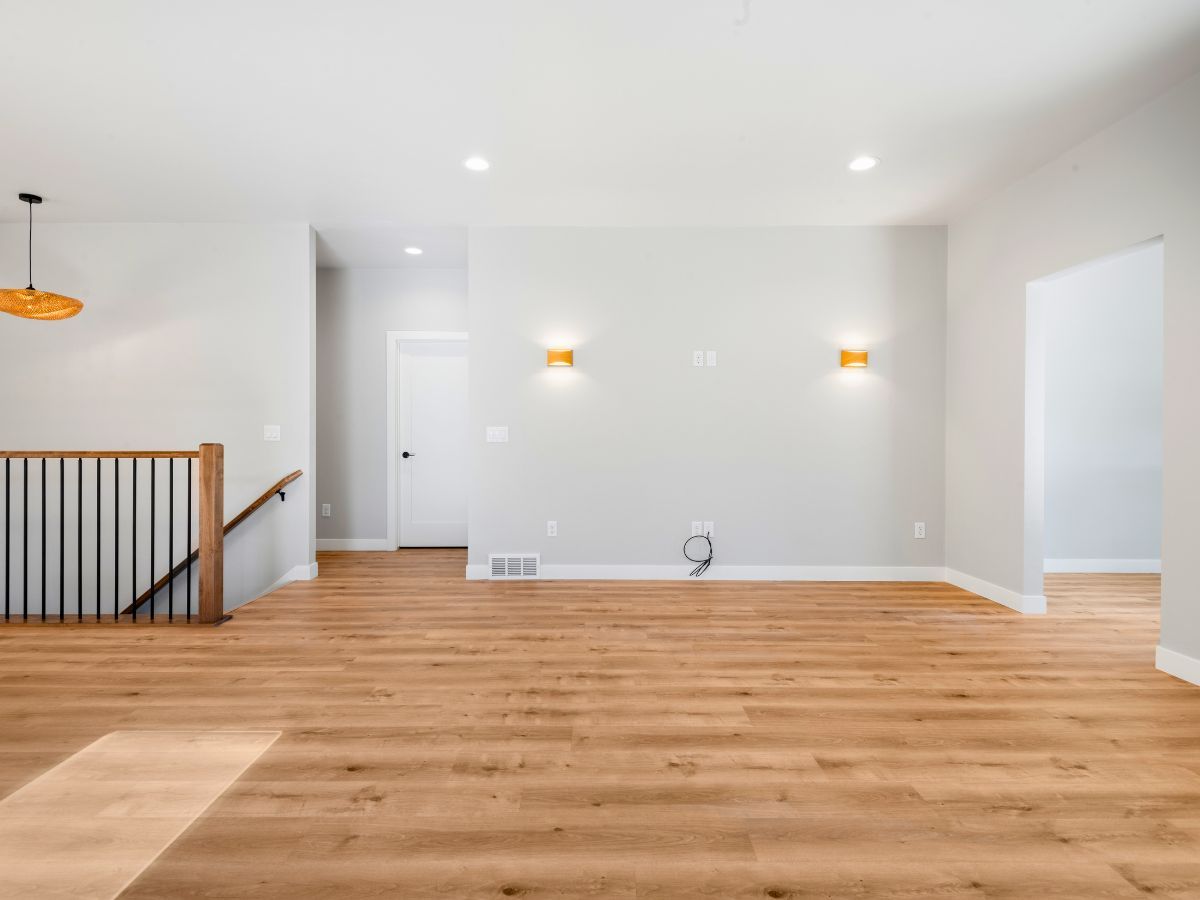 An empty living room with hardwood floors and white walls.