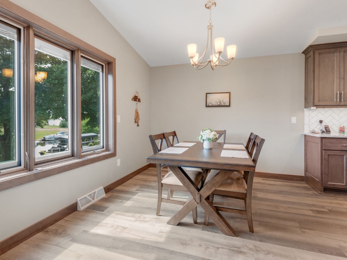 A dining room with a wooden table and chairs and a chandelier.