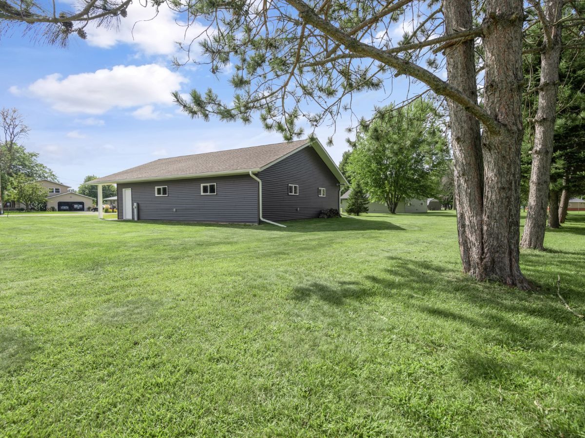 A house is sitting in the middle of a lush green field surrounded by trees.