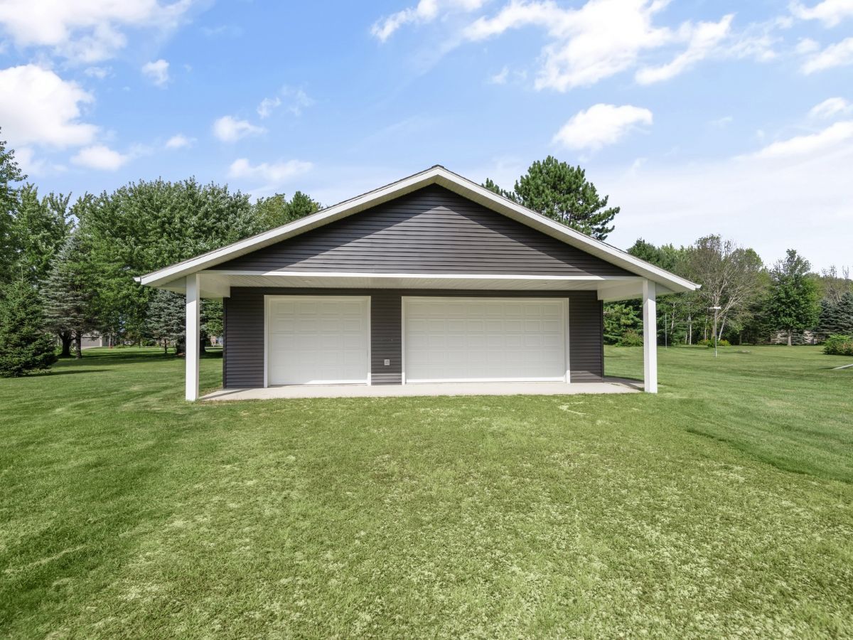A large garage is sitting in the middle of a lush green field.