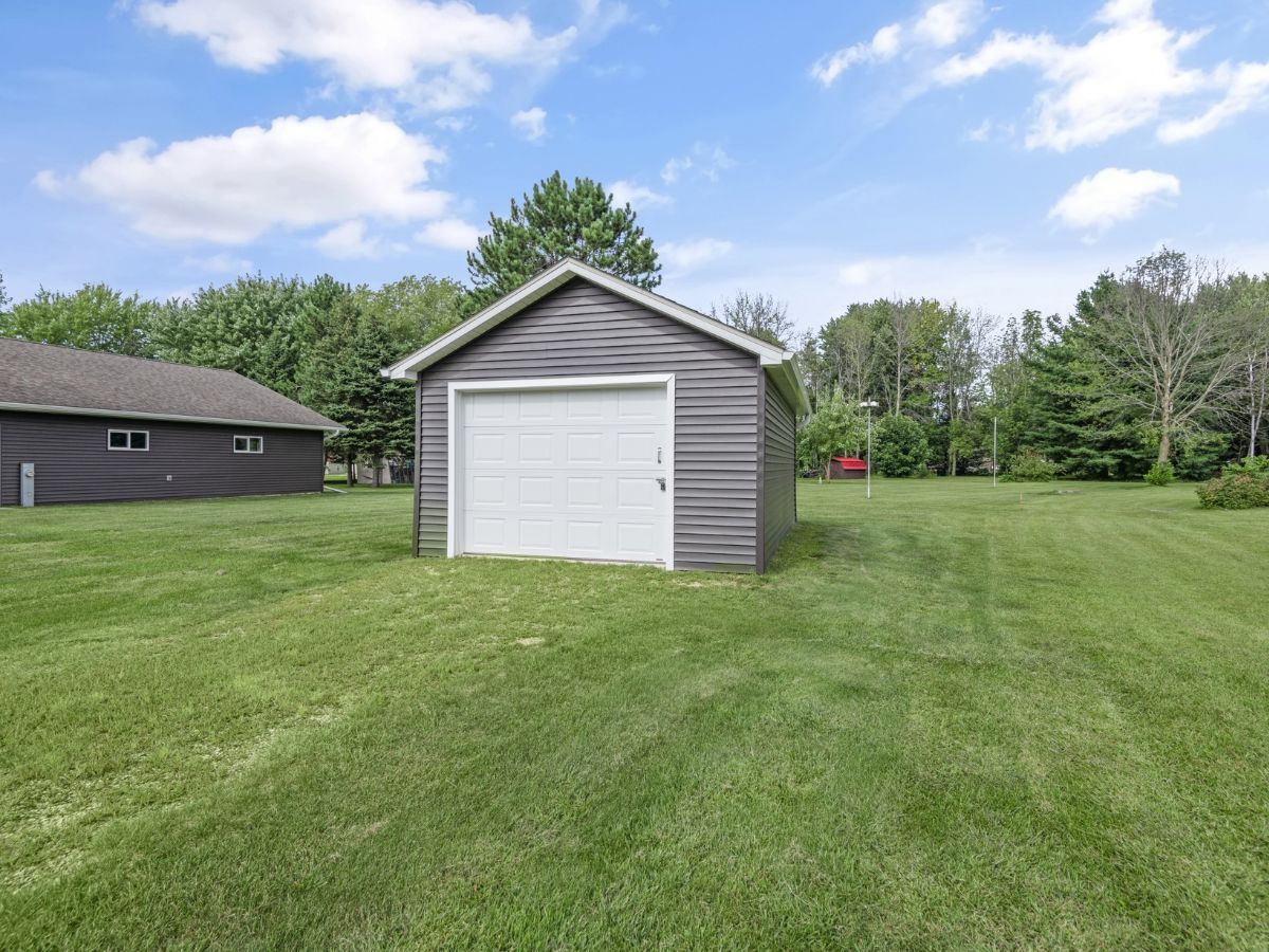 A garage with a white door is sitting in the middle of a lush green field.
