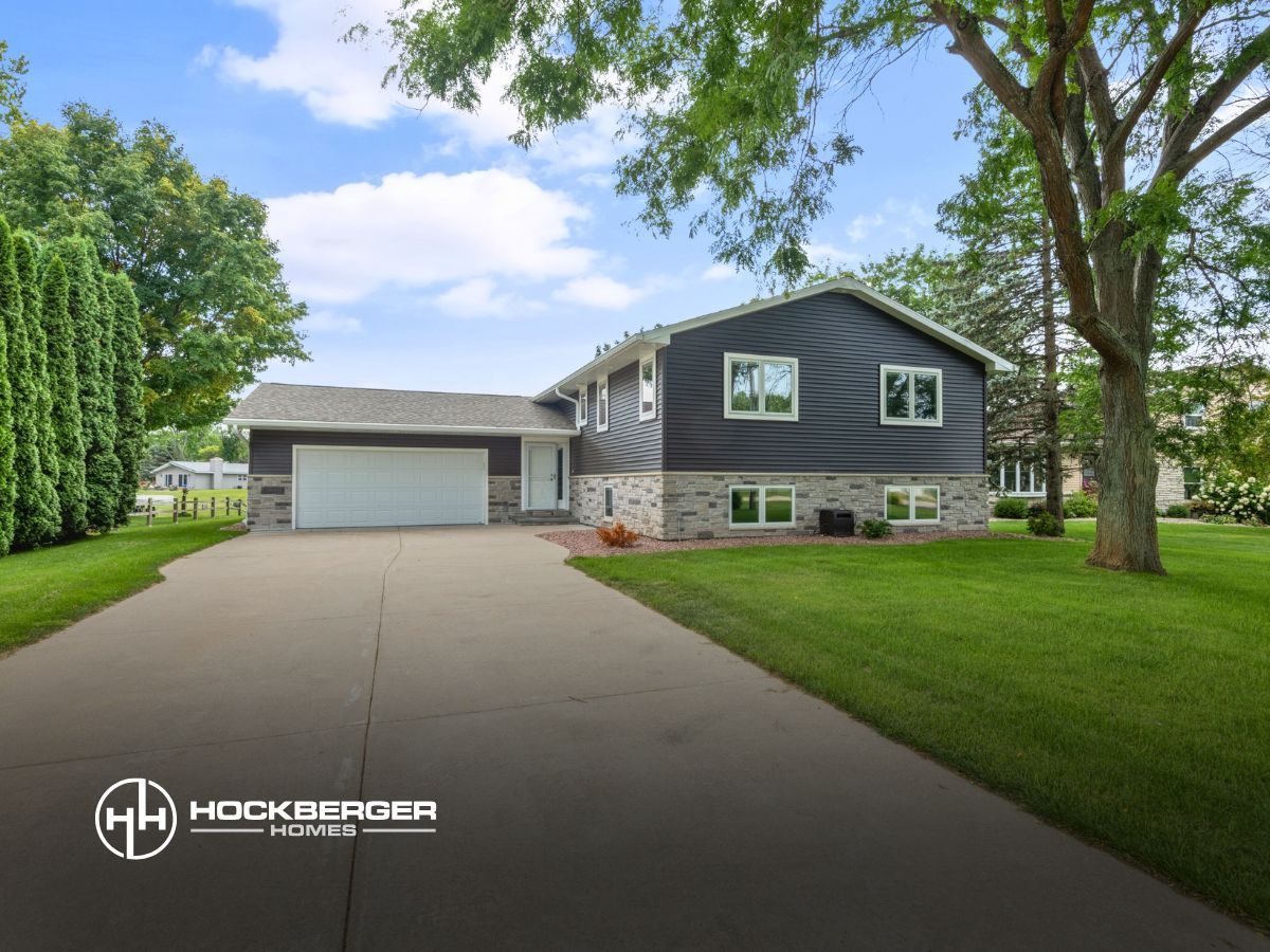 A house with a driveway and a tree in front of it