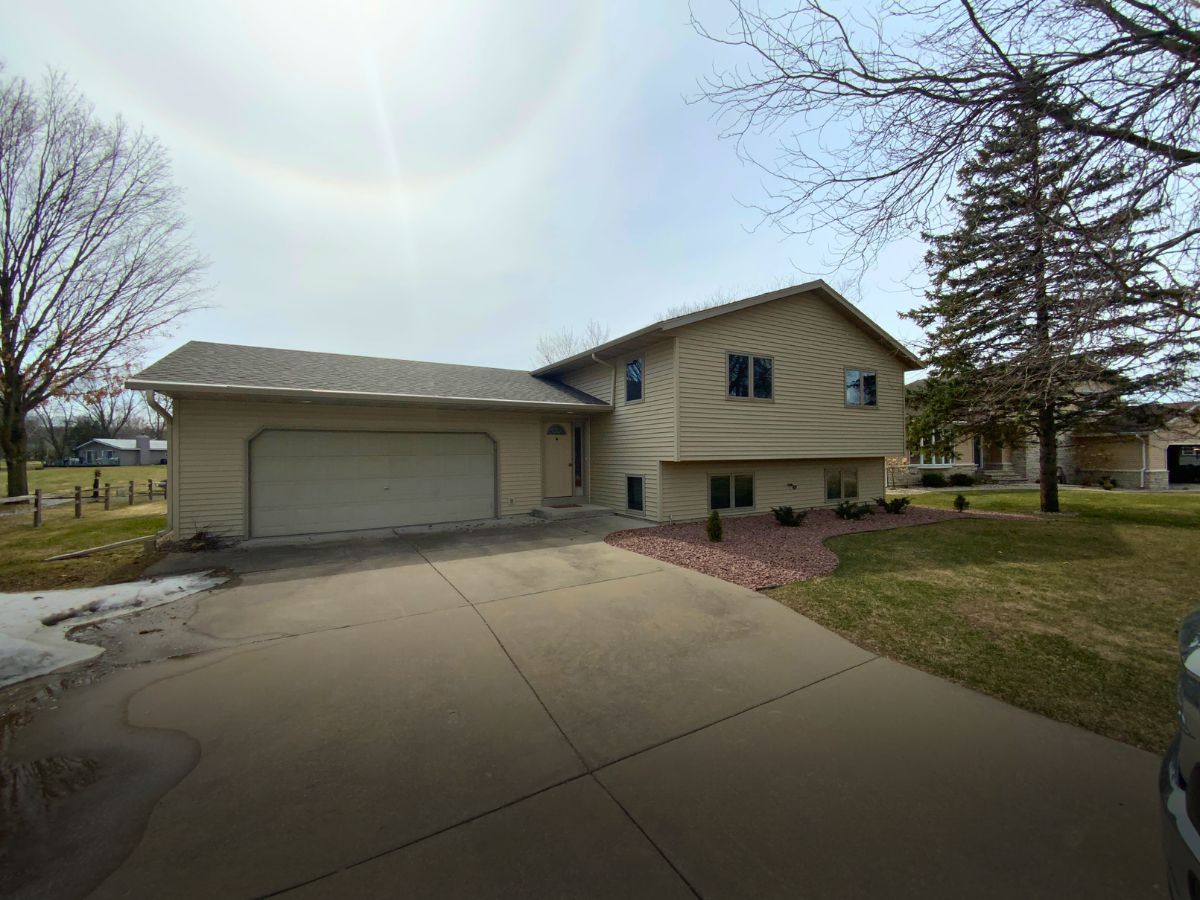 A house with a garage and a car parked in front of it.