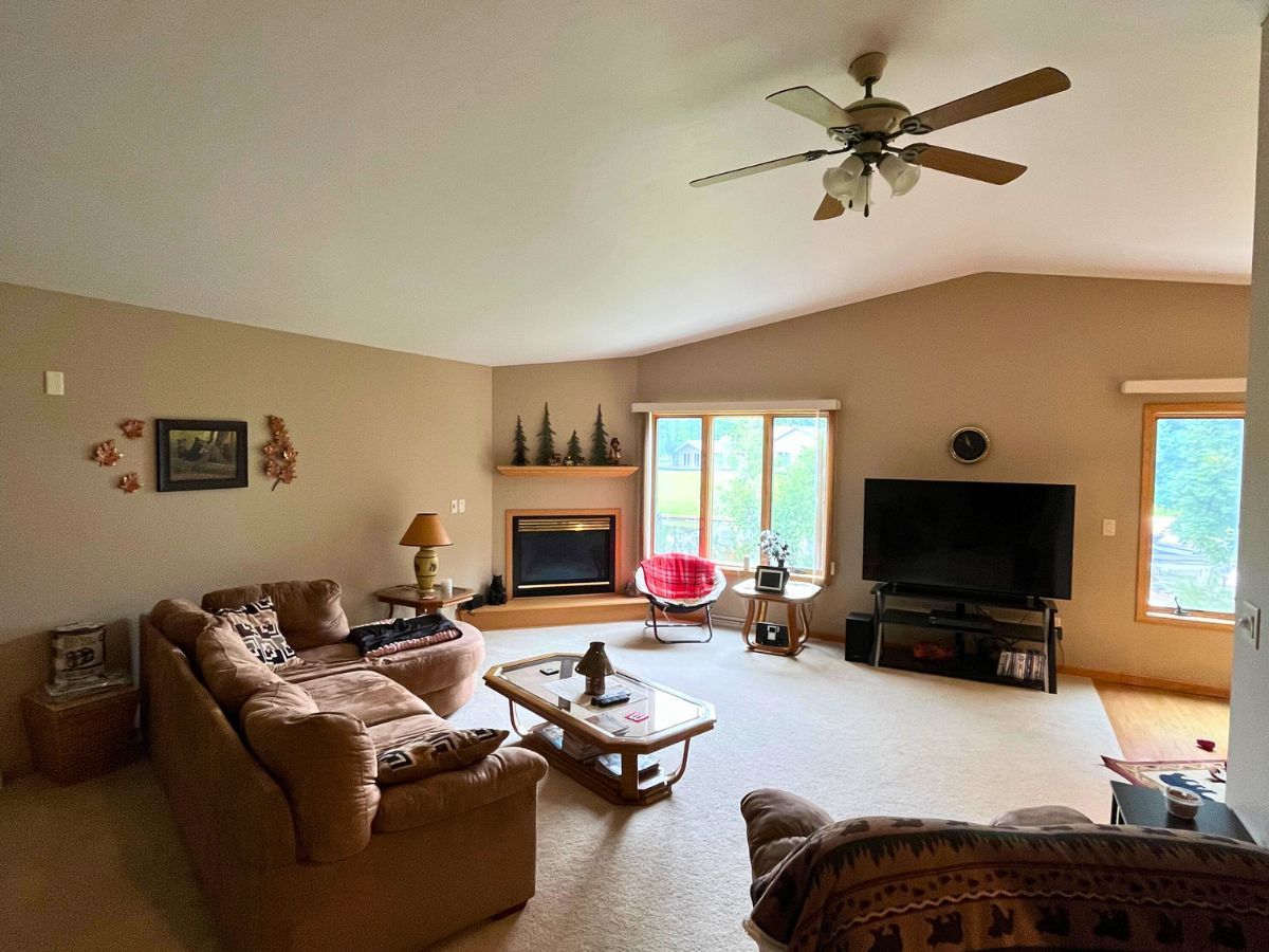 A living room with a couch , television , fireplace and ceiling fan.