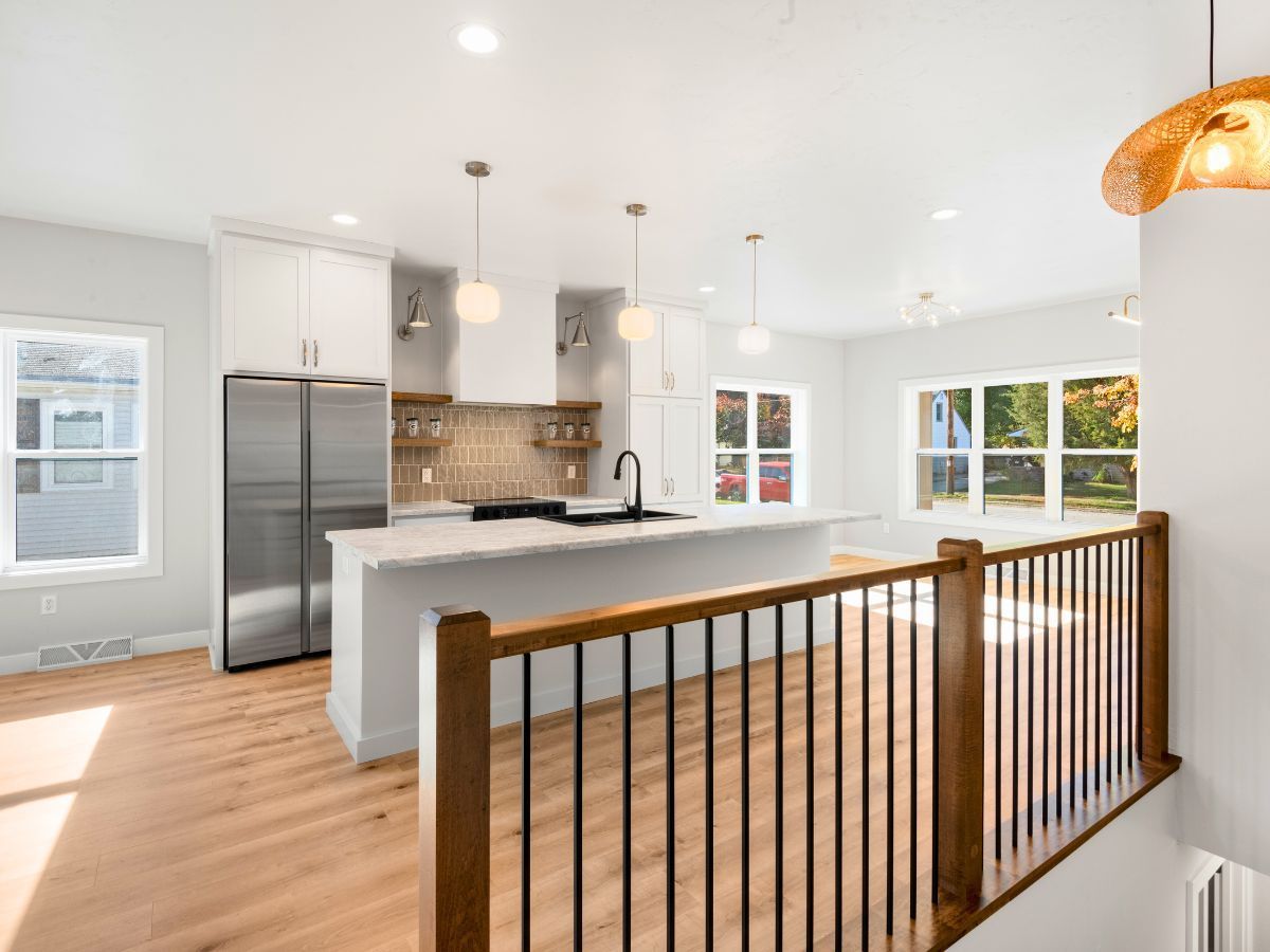 A kitchen with stainless steel appliances and a wooden staircase leading to it.