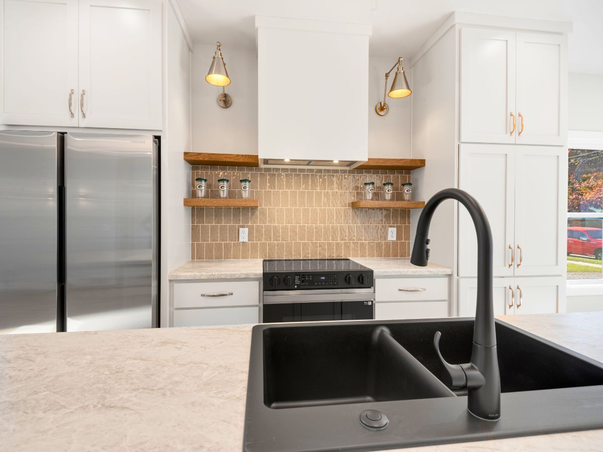 A kitchen with a black sink , stove and refrigerator.