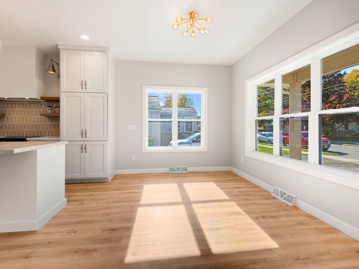 An empty room with hardwood floors and a lot of windows.
