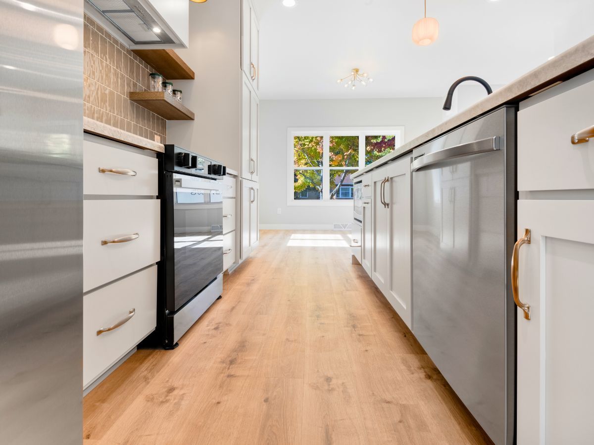A kitchen with stainless steel appliances and wooden floors.